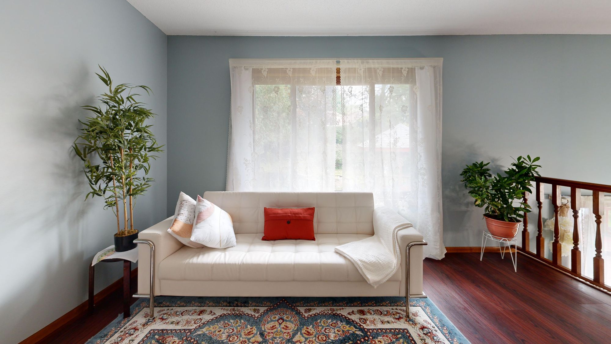 Sunlit living room with a white sofa and large windows